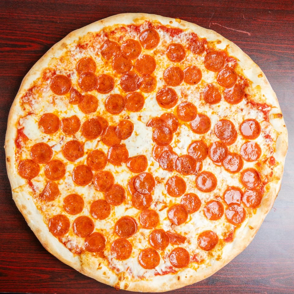 Large pepperoni pizza with melted cheese and tomato sauce on a dark wooden table.